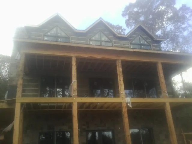 Dormers and porch framing on a large log home under construction — Roof Coating work by our crew in Monroe